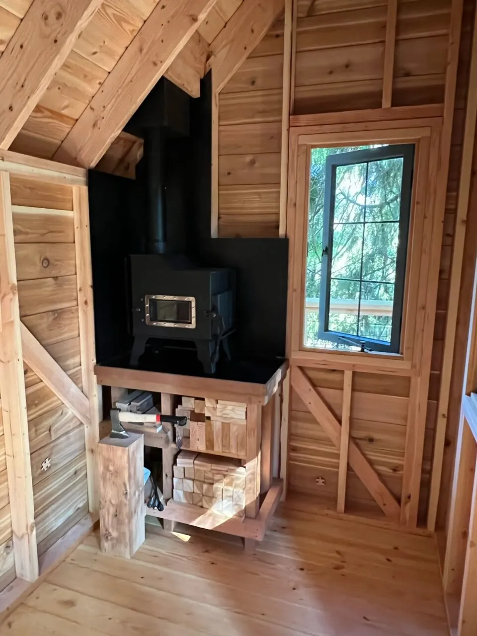 Wall-mounted Caboose tiny wood stove installed in a wood-paneled cabin